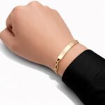 Gold tone Figaro bracelet worn on the wrist